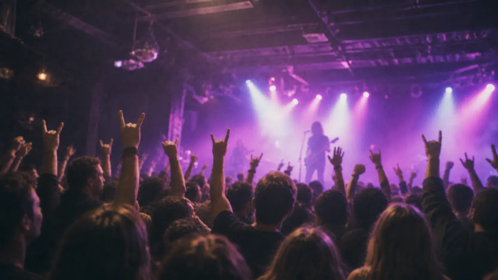 A live music crowd raising their hands toward the stage